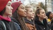 © EvgeniiasArt - Diverse group of four young women standing outdoors in winter attire at the demonstration