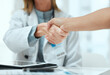 © KayExam/peopleimages.com - Consulting, doctor and handshake with people in hospital office for medical agreement or meeting. Deal, interview or partnership with healthcare professional and patient shaking hands in clinic