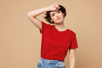 Wall Mural - Young sad exhausted ill woman she wear red t-shirt casual clothes hand on forehead look camera suffer from headache isolated on plain pastel light beige background studio portrait. Lifestyle concept.