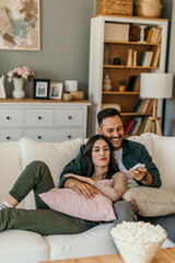 Shot of a beautiful mid adult happy couple sitting on a couch at home and watching tv