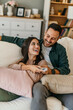 © La Famiglia - The couple Watches TV together while Sitting on a Couch in the Living Room and Bonding