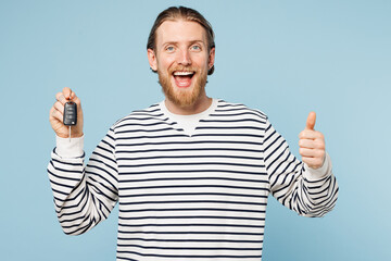 Canvas Print - Young smiling happy man he wear striped sweatshirt casual clothes hold in hand car key fob keyless system show thumb up isolated on plain pastel light blue cyan background studio. Lifestyle concept.