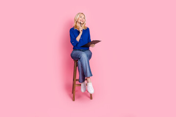 Poster - Full body photo of attractive retired woman sit chair write paperholder dressed stylish blue clothes isolated on pink color background