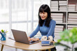 © David - Happy asian woman using laptop while working remotely from home in living room
