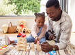 © Nina2024/peopleimages.com - Black man, play and building blocks with girl learning from father on floor of living room. Kid, growth and toys for child development with dad teaching daughter in home lounge for education