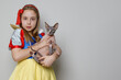 © millaf - Beautiful kid girl theater actress in SnowWhite costume smiling and holding cat on white background