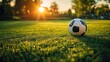 ©  Dreamy Shots - Soccer ball resting on green grass field at sunset, highlighting a peaceful moment before a game, with sunlight creating a serene, warm atmosphere