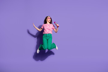 Wall Mural - Full body photo of attractive young woman sing karaoke microphone jumping dressed stylish pink clothes isolated on violet color background