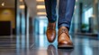 © Andrii - Businessman walking confidently on polished floor in office hallway wearing brown leather shoes during work hours