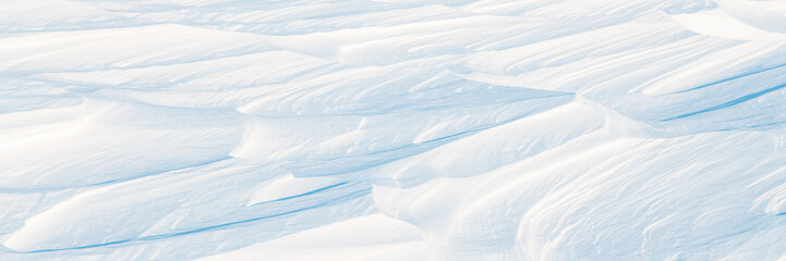 Snow texture. Wind sculpted patterns on snow surface. Wind in the tundra and in the mountains on the surface of the snow sculpts patterns and ridges (sastrugi). Arctic, Polar region. Winter background