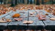 © Wimon - A rustic wooden table set in an autumn park, blanketed with freshly fallen leaves in warm shades of gold and crimson, creating a cozy seasonal scene.