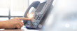 © chinnarach - close up employee call center man hand point to press button number on telephone landline (VOIP system) at office desk with for communication industry and business technology and contact us concept