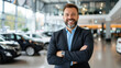 © khonkangrua - Confident car salesman in a showroom, smiling and ready to assist customers in purchasing vehicles.