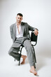 © Elina Leonova - Man in grey costume sits on the chair, barefoot. In studio, fashion