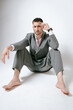 © Elina Leonova - Handsome man in grey suit sits on the floor barefoot