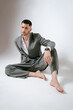 © Elina Leonova - Handsome man in grey suit sits on the floor barefoot