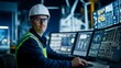 © Oulaphone - A focused engineer in a hard hat operates modern control panels in a tech-driven environment, highlighting industrial innovation and safety.