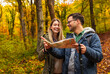 © Zoran Zeremski - Smiling couple with backpacks hiking together in forest using map for direction.
