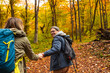 © Zoran Zeremski - Smiling couple with backpacks hiking together in forest holding hands.