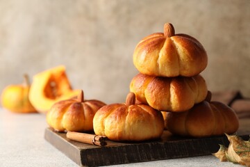 Wall Mural - Tasty pumpkin shaped buns and cinnamon on light grey table, closeup