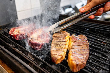 Sticker - Close-up of juicy steaks being grilled, with smoke rising, showcasing the sizzle and texture of the meat. Perfect for BBQ, cooking, and food-related themes. High-quality image with vibrant colors.