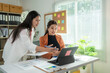 © Wasana - Two asian businesswomen working and discussing using digital tablet in office