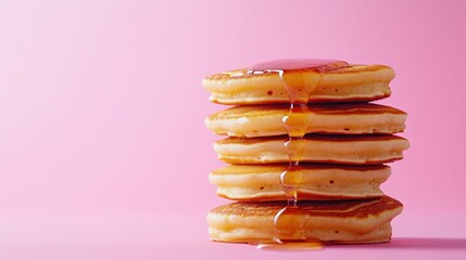 Wall Mural - A stack of fluffy pancakes drizzled with syrup on a pink background.