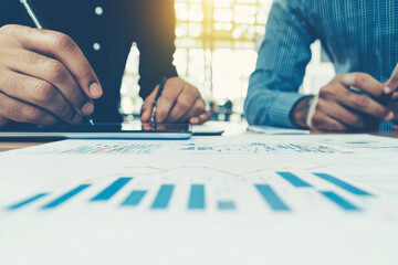 Two people work on a project, looking at charts and graphs.