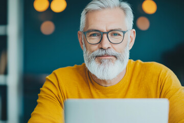 Canvas Print - Smiling senior man in a yellow sweater looks at the camera.