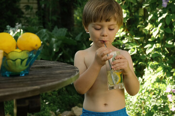 Small child drinking lemonade in summer back yard