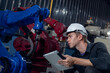 © surachetkhamsuk - Engineer standing by robotic arm and operating machine in industry factory, technician worker check for repair maintenance electronic operation