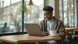 © JuLady_studio - African american teen studying online in coffee shop with laptop, focused on homework. The relaxed cafe setting creates cozy atmosphere, making this image ideal for themes related to online learning.