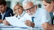 © angel_nt - A senior professional analyzes paperwork while engaged in a discussion with coworkers in a contemporary office environment, emphasizing collaboration and strategy