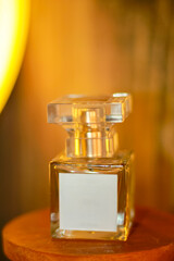 glass bottle containing women's perfume liquid highlighted by light with wooden board background