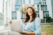 © Dusan - Young businesswoman is working on laptop in front of modern building
