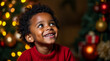 © zamuruev - Young child with curly hair beams with joy while perched in front of beautifully decorated Christmas tree filled with colorful ornaments and warm lights