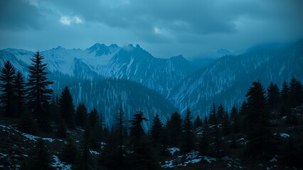 Wall Mural - Silhouetted trees stand against a dramatic backdrop of snow-capped mountains under a twilight sky.