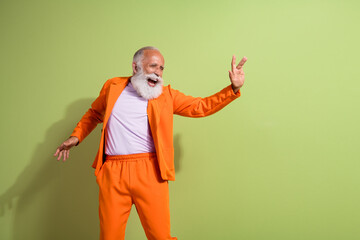 Poster - Portrait of funky eccentric grandfather dancing empty space wear orange suit isolated on green color background