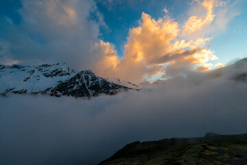 Beautiful view of the harsh snowy peaks of the Elbrus mountains at sunset with low clouds. The North Caucasus. Russia