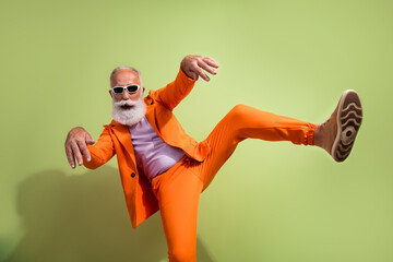 Poster - Portrait of funky eccentric grandfather dance footwear ad wear orange suit isolated on green color background