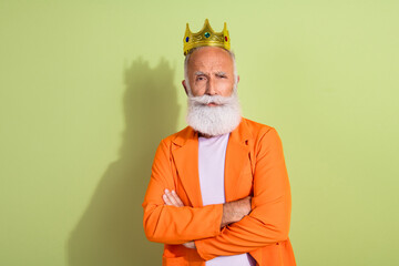 Poster - Portrait of aged man performer golden crown crossed arms wear orange suit isolated on green color background