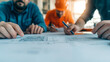 © Vertigo Images - Close-up of hands reviewing blueprints.
