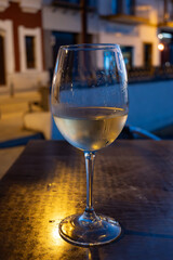 Glass of cold dry white wine served outdoor in cafe at night in historical Triana district, Sevilla, Spain, close up