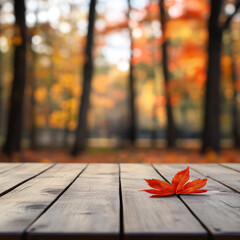 A plain wooden table with a blurry background of fall trees and a red leaf. This image is perfect for showing off your products in a cozy, autumn setting.