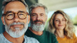 © Vertigo Images - Smiling man with a gray beard and glasses in focus with two other people out of focus behind him.