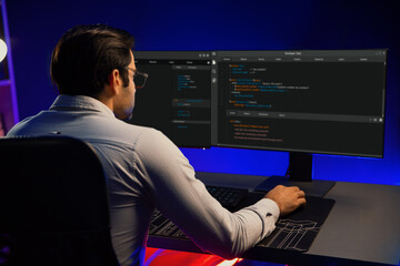 Working smart IT developer analyzing data software development on two pc screen, creating application program updated version online website page system online at neon light cyber office. Surmise.