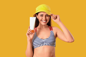 Sticker - Young woman with sunscreen cream on yellow background