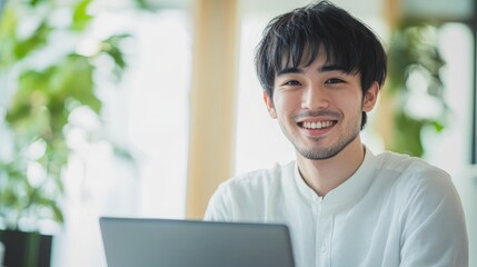 Smiling Young Man Using Laptop in a Bright Workspace