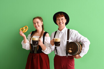 Sticker - Young couple in traditional German clothes with beer and pretzel on green background