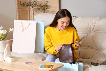 Wall Mural - Young Asian woman with new bag at home. Online shopping